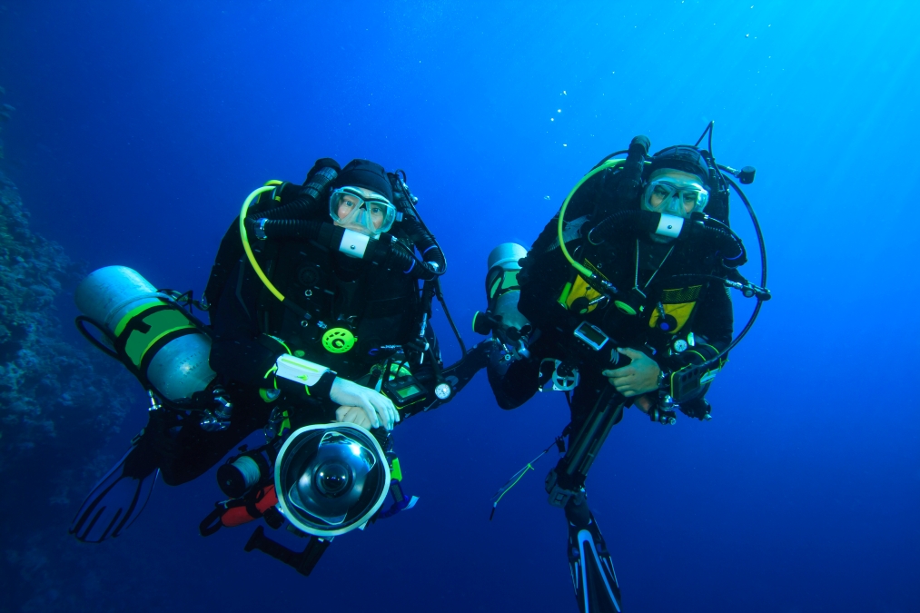 Comparison photo showing fish behavior around bubble-producing diver vs silent rebreather diver